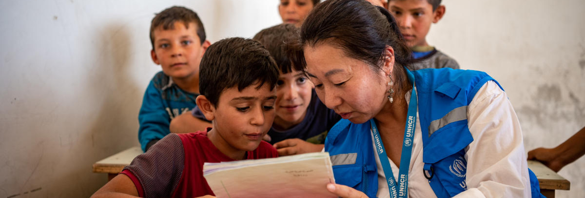 Integrante de ACNUR lee un libro con un niño, en Alepo, Siria.