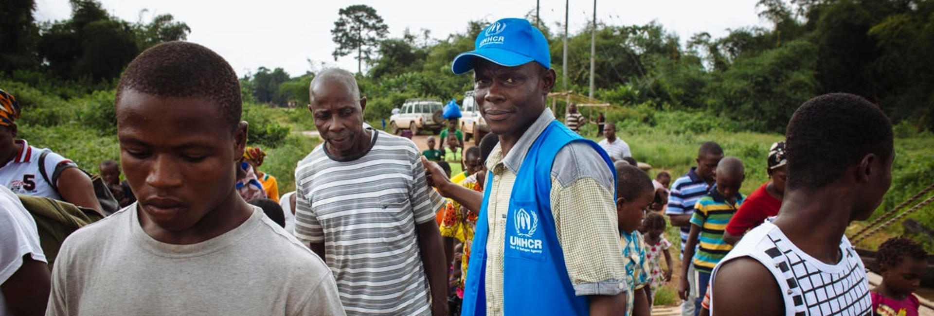Un trabajador de ACNUR ayuda a un grupo de personas refugiadas a abordar un ferry que las llevará de vuelta a Côte d'Ivoire, su país de origen.