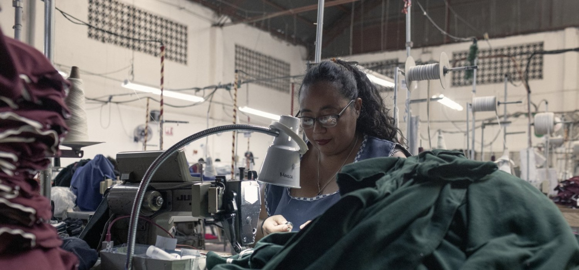 Una mujer trabaja en una fábrica con una máquina de coser.