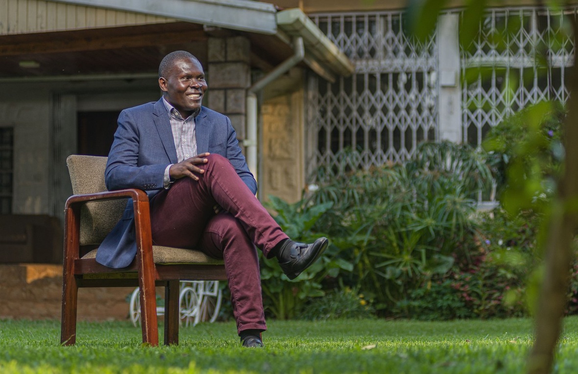 Un hombre sonriente sentado en una silla en un jardín