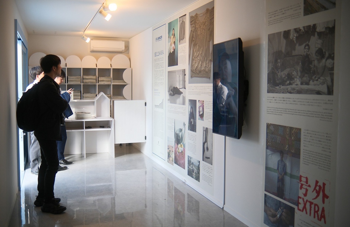 Una persona viendo unos paneles con fotos y una pantalla en una sala.