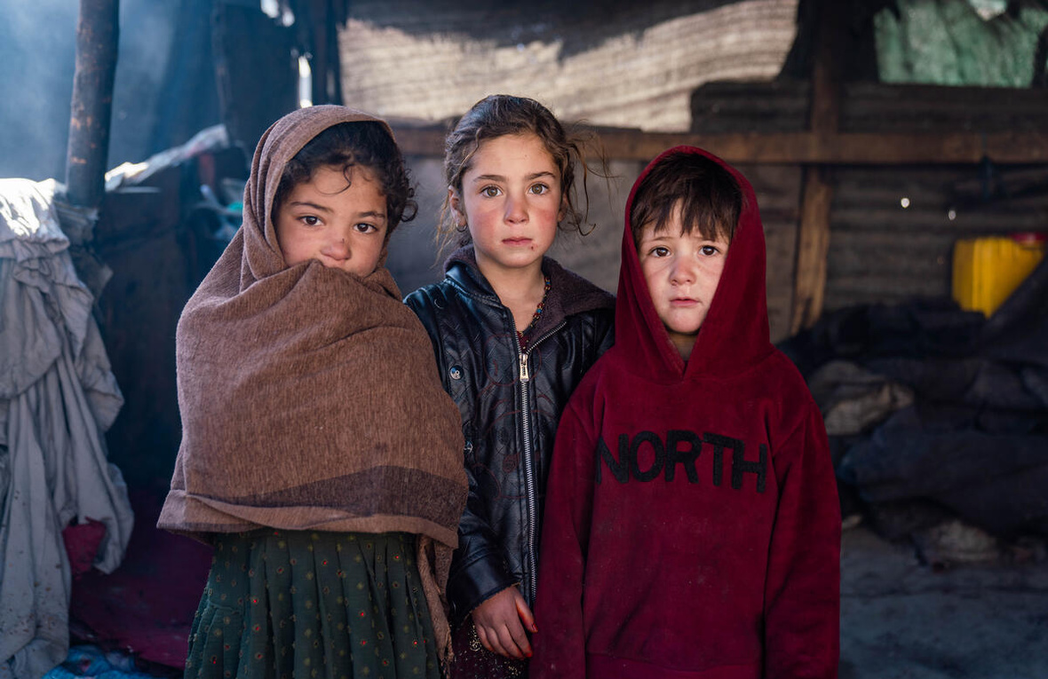 Niños afganos desplazados internos frente a la tienda de campaña de su familia en Kabul, febrero de 2025.