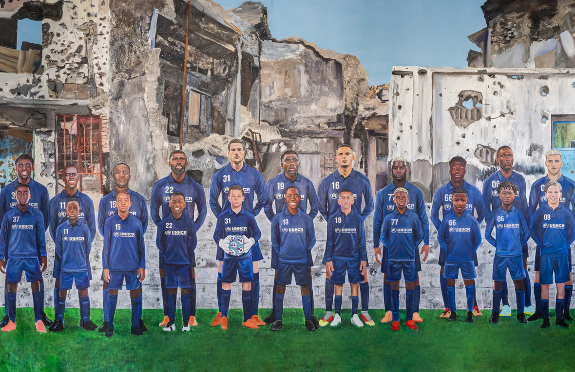 El mural, de 3 metros por 2, muestra al equipo alineado en una cancha de fútbol con sus yo infantiles de pie frente a ellos. Detrás de los jugadores en la grama se observa un telón de fondo de guerra y conflicto.