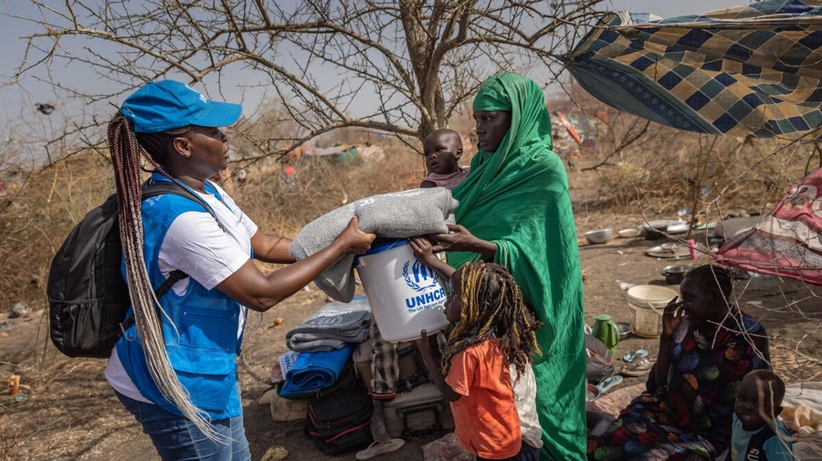 Una trabajadora de ACNUR entrega artículos básicos de ayuda a una refugiada sudanesa