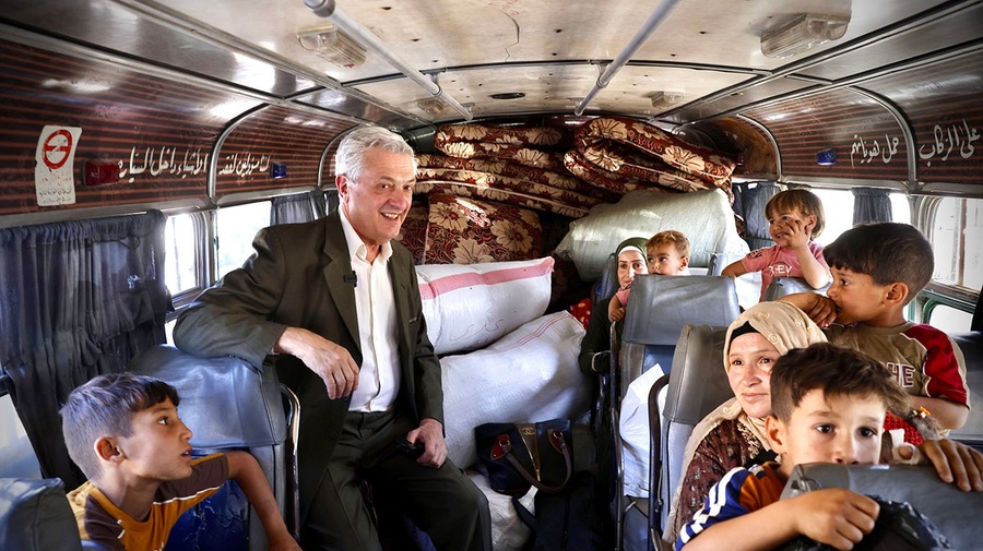 En esta foto tomada dentro de un bus el Alto Comisionado posa junto a los pasajeros, mujeres niñas y niños.