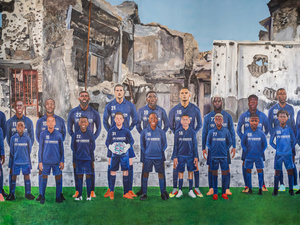 El mural, de 3 metros por 2, muestra al equipo alineado en una cancha de fútbol con sus yo infantiles de pie frente a ellos. Detrás de los jugadores en la grama se observa un telón de fondo de guerra y conflicto.