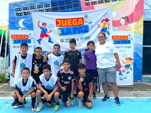 Un grupo de ocho niños, una niña y una mujer adulta con uniformes deportivos