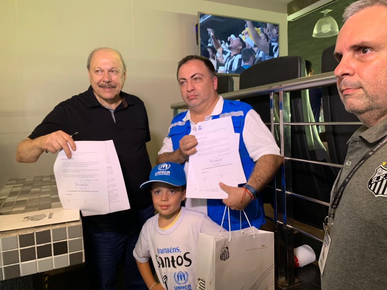 Representante do ACNUR, Jose Egas, e o Presidente do Santos FC, José Carlos Peres, apresentam termo assinado durante o intervalo do jogo 