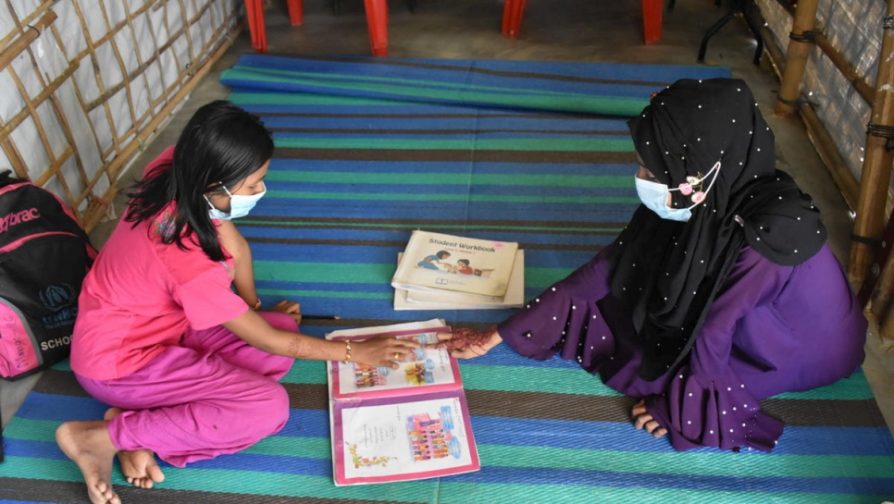 Nur Ayna (à direita) interage com uma estudante refugiada rohingya no campo de refugiados de Kutapalong, Bangladesh