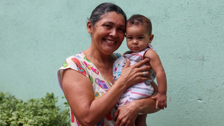 A venezuelana líder comunitária e aluna de português, Yalethe, carrega seu neto Daniel, nascido no Brasil 