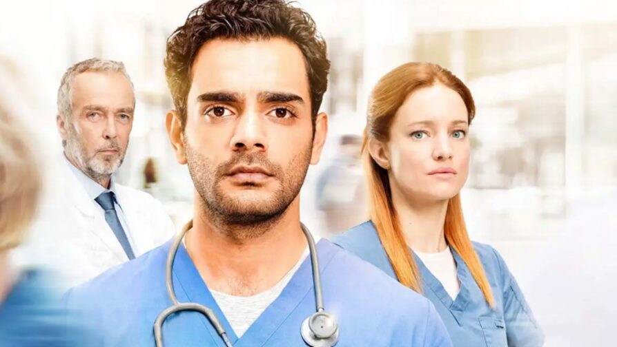 Nesta foto são representados 3 médicos, sendo dois homens e uma mulher, os quais estão de frente para a câmera, com rostos sérios e uniformes.