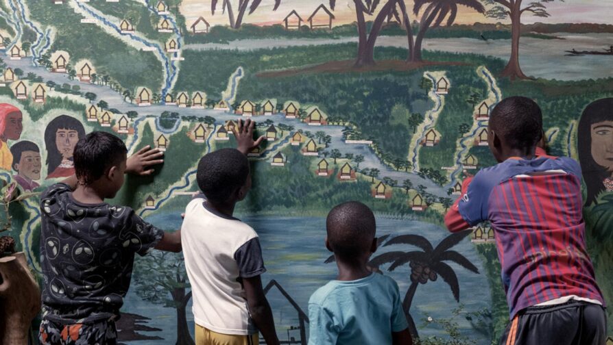 Crianças na aldeia de Noanamá olham para um mural que retrata as comunidades que vivem ao longo do Rio San Juan e seus afluentes. © ACNUR/Nicolo Filippo Rosso 