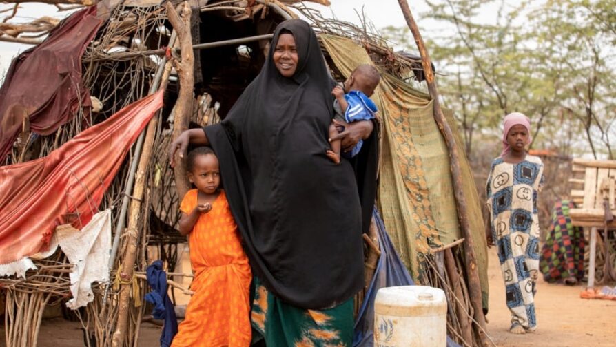 Mãe com dois dos seus dez filhos em frente a um acampamento no Quênia.