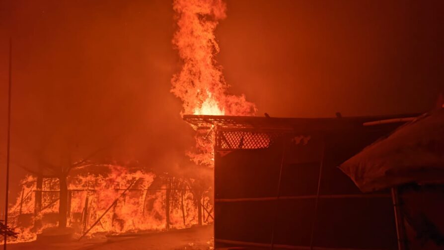 Abrigo aparece em meio a chamas, enquanto estrutura semelhante é tomada por fogo, atrás.
