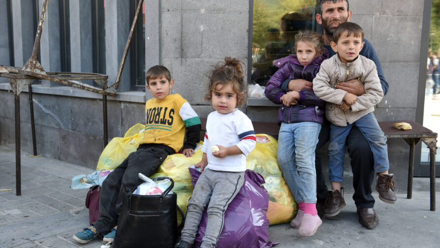 Pai com dois filhos no colo e outros dois em cima de bolsas e sacos plásticos, com pertences da família, na cidade de Goris, no sul da Armênia, junto com dezenas de milhares de refugiados.