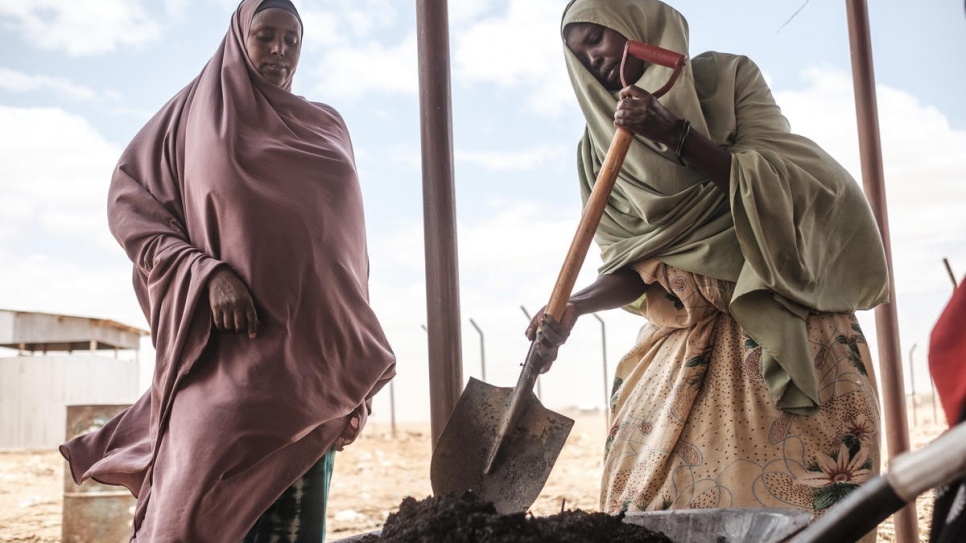 Com uma pá, a refugiada somali Saredo Abdi, 26, (à direita) transforma subprodutos da árvore prosopis juliflora em um centro de processamento em Bur Amino, Etiópia