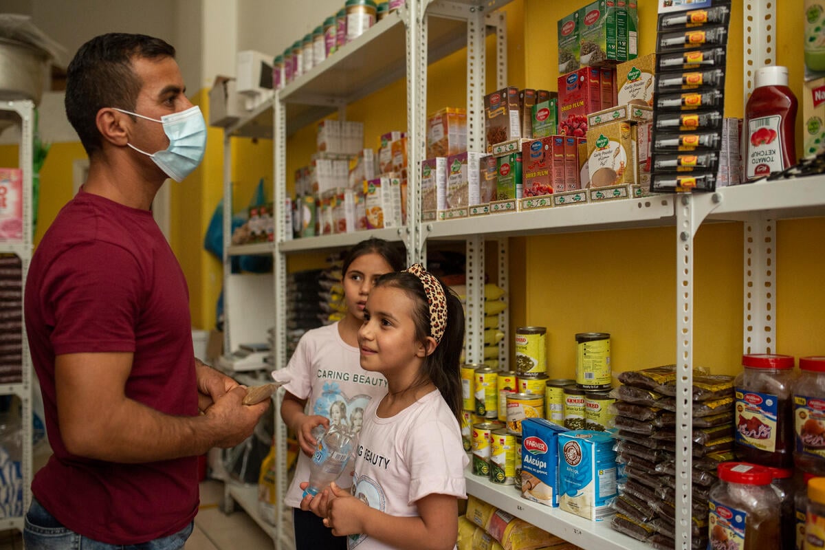 A man and his two daughters look at items at a small grocery store