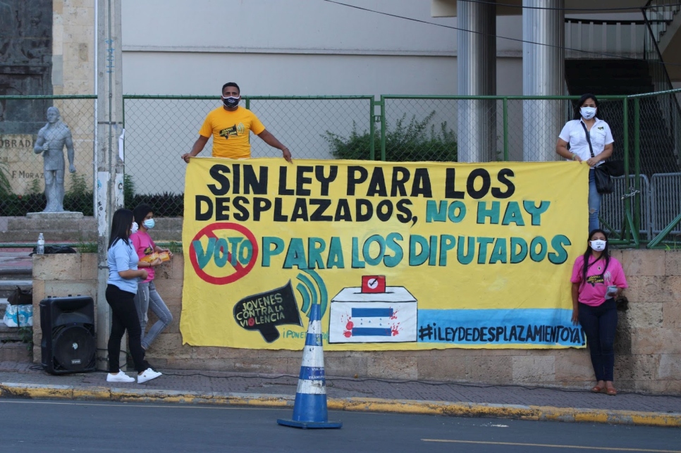 Protestors hold a giant sign which says 'Sin ley para los desplazados, no hay voto para los diputados'
