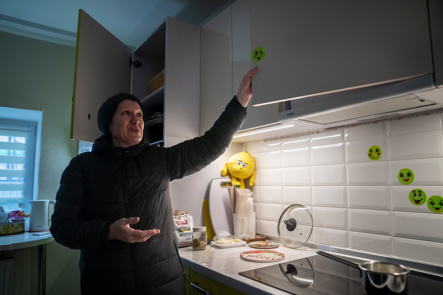 Una mujer señala las pegatinas que cubren los daños causados por municiones en la cocina de su casa.
