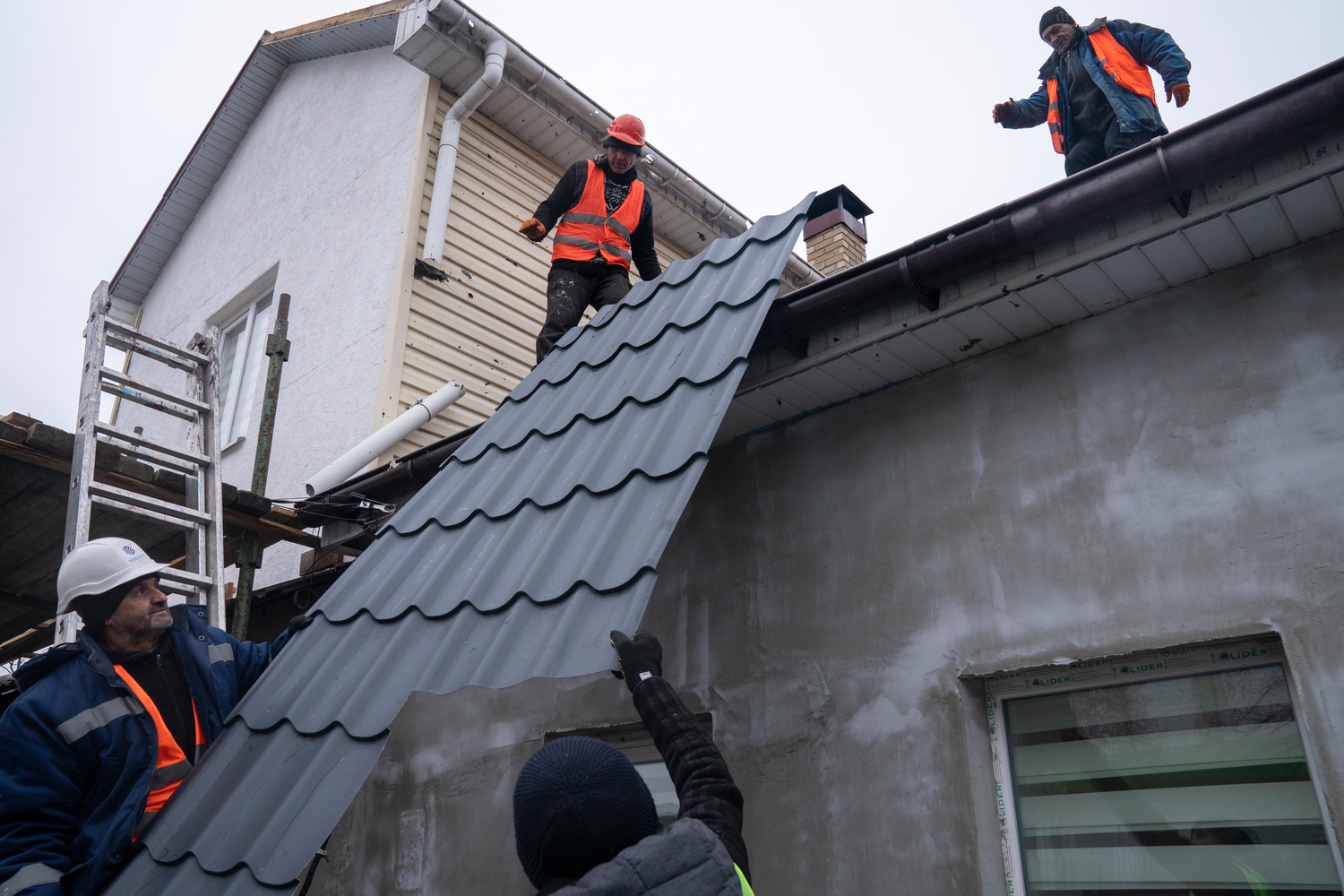 Obreros levantan una nueva sección del tejado de una casa en Ucrania.