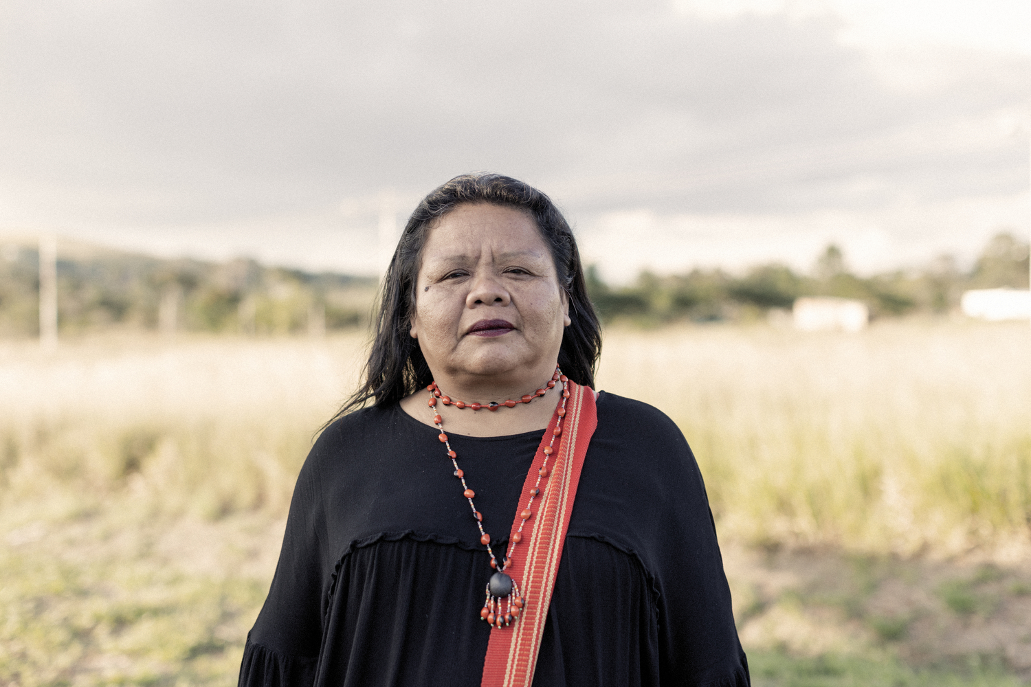 Mujer con camisa negra, faja roja y collar de cuentas Mujer con camisa negra, faja roja y collar de cuentas