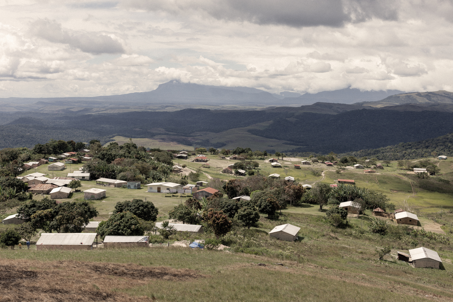 Vista de un pueblo con verdes colinas y montañas al fondo