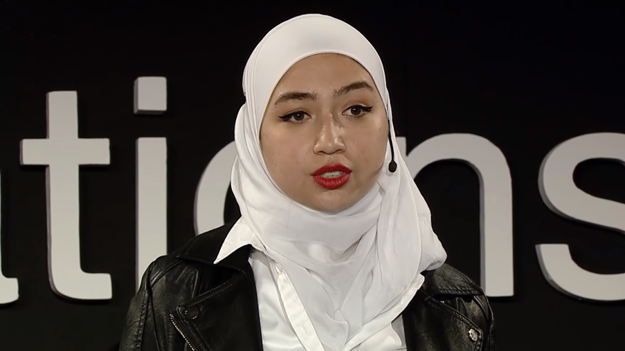 Una joven siria, que lleva puesto un hiyab color blanco, charla con un pequeño micrófono
