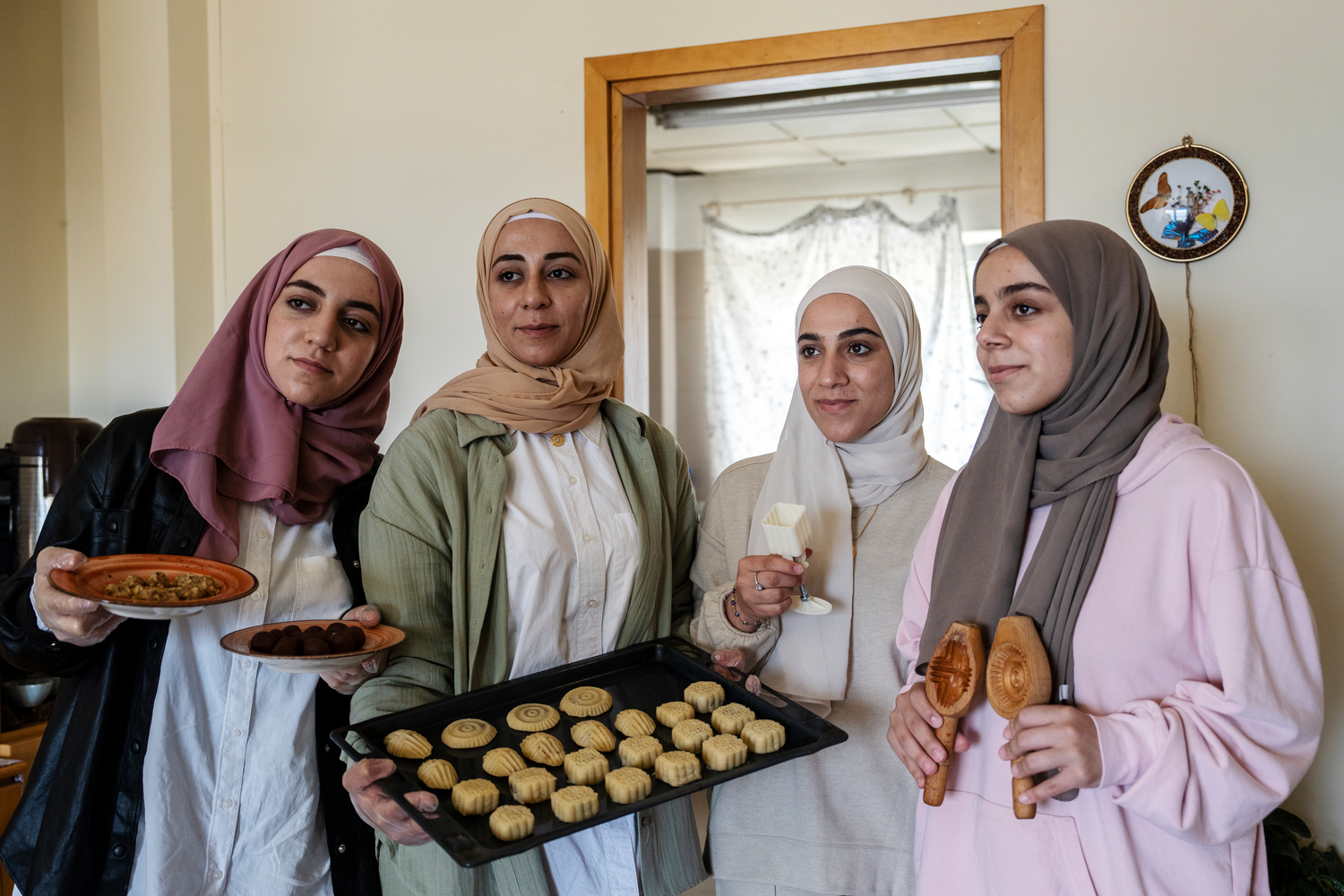 Cuatro jóvenes con pañuelos en la cabeza sostienen una bandeja de galletas