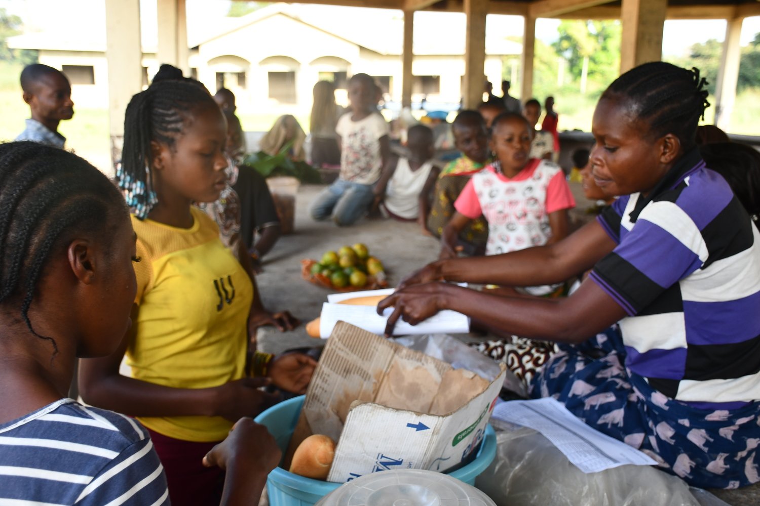 Una mujer en un mercado en República del Congo le entrega a su clienta una hogaza de pan envuelta en papel