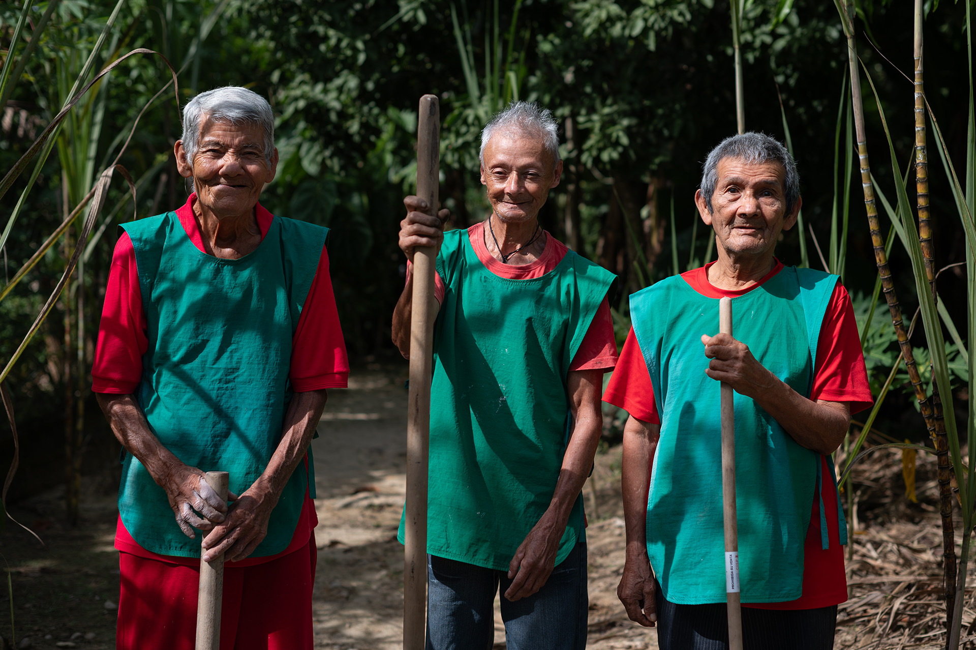 Tres hombres mayores posan sonriendo con sus herramientas de trabajo.