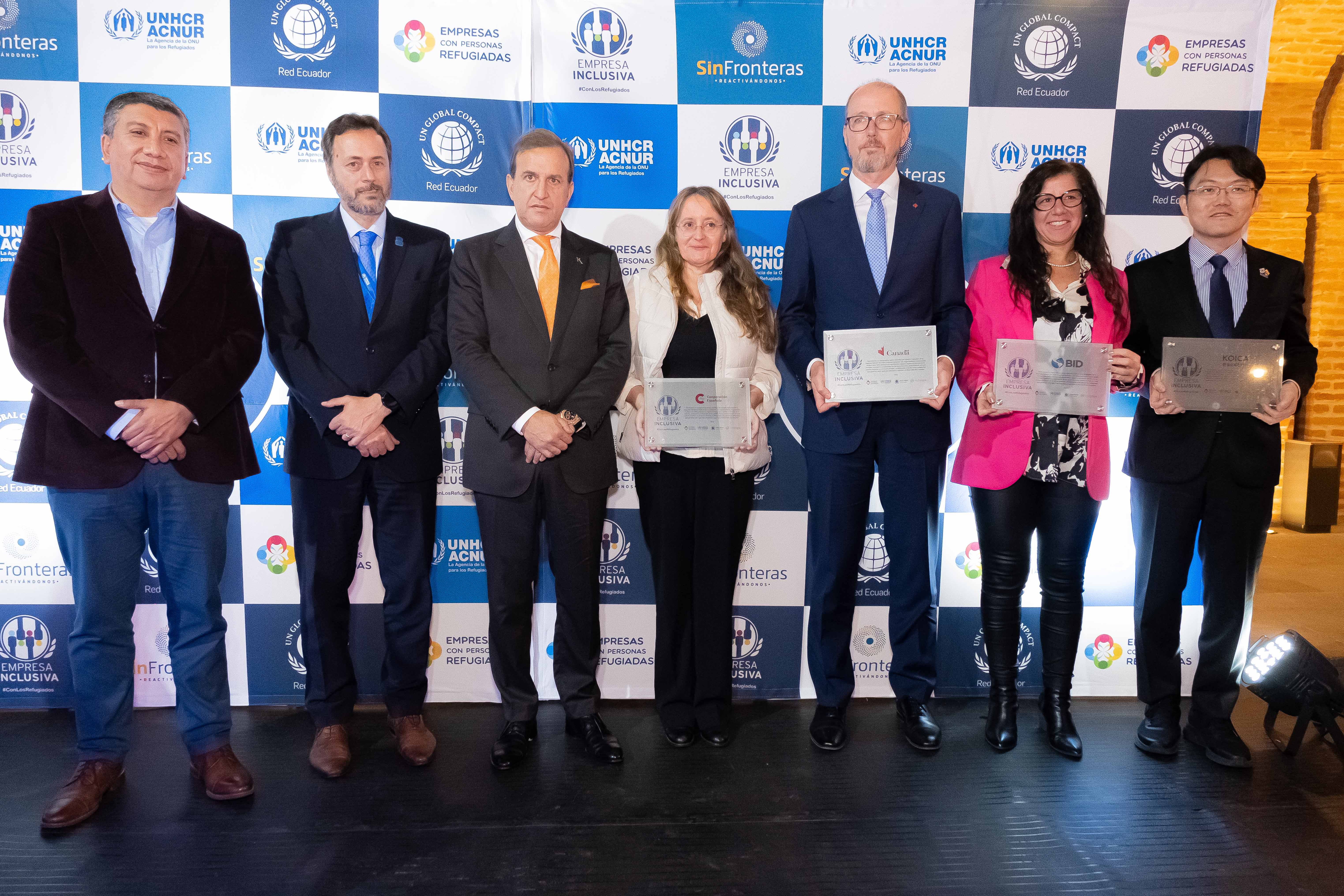 Un grupo de 4 hombre y 2 mujeres vestidos formalmente, posan ante la cámara. Cuatro de ellos muestran un certificado como galardón