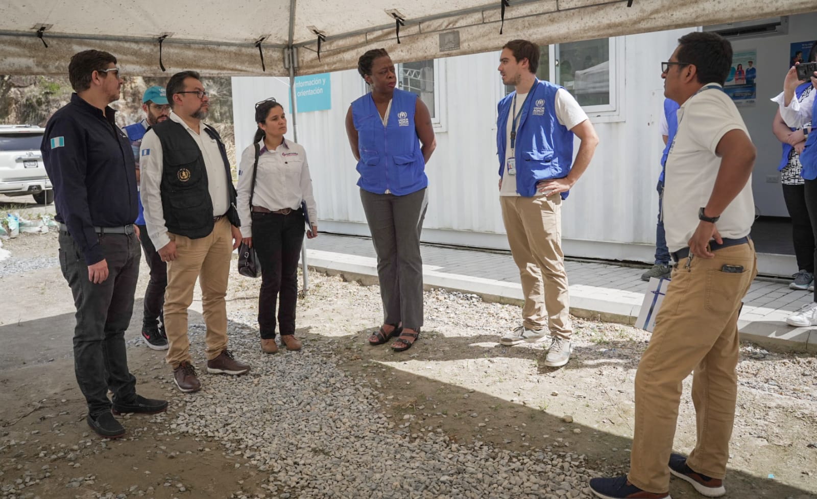 Representantes de las entidades que participaron en la misión están reunidos hablando, de pie, fuera de las instalaciones del centro de atención.