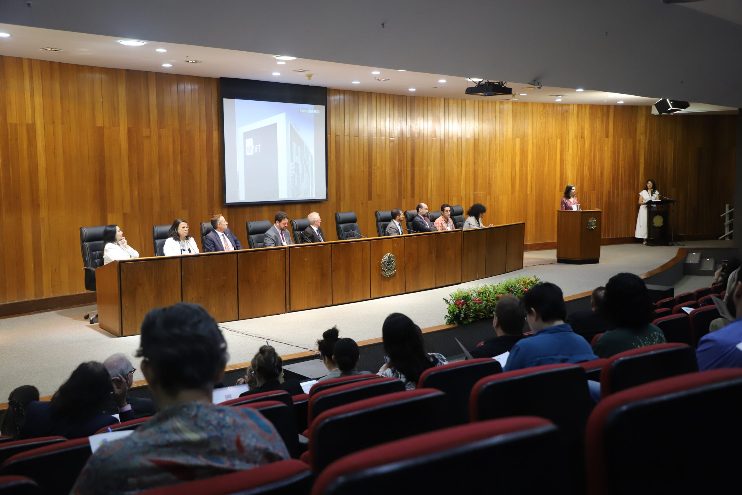 Panel de una decena de personas, frente a un auditorio lleno.