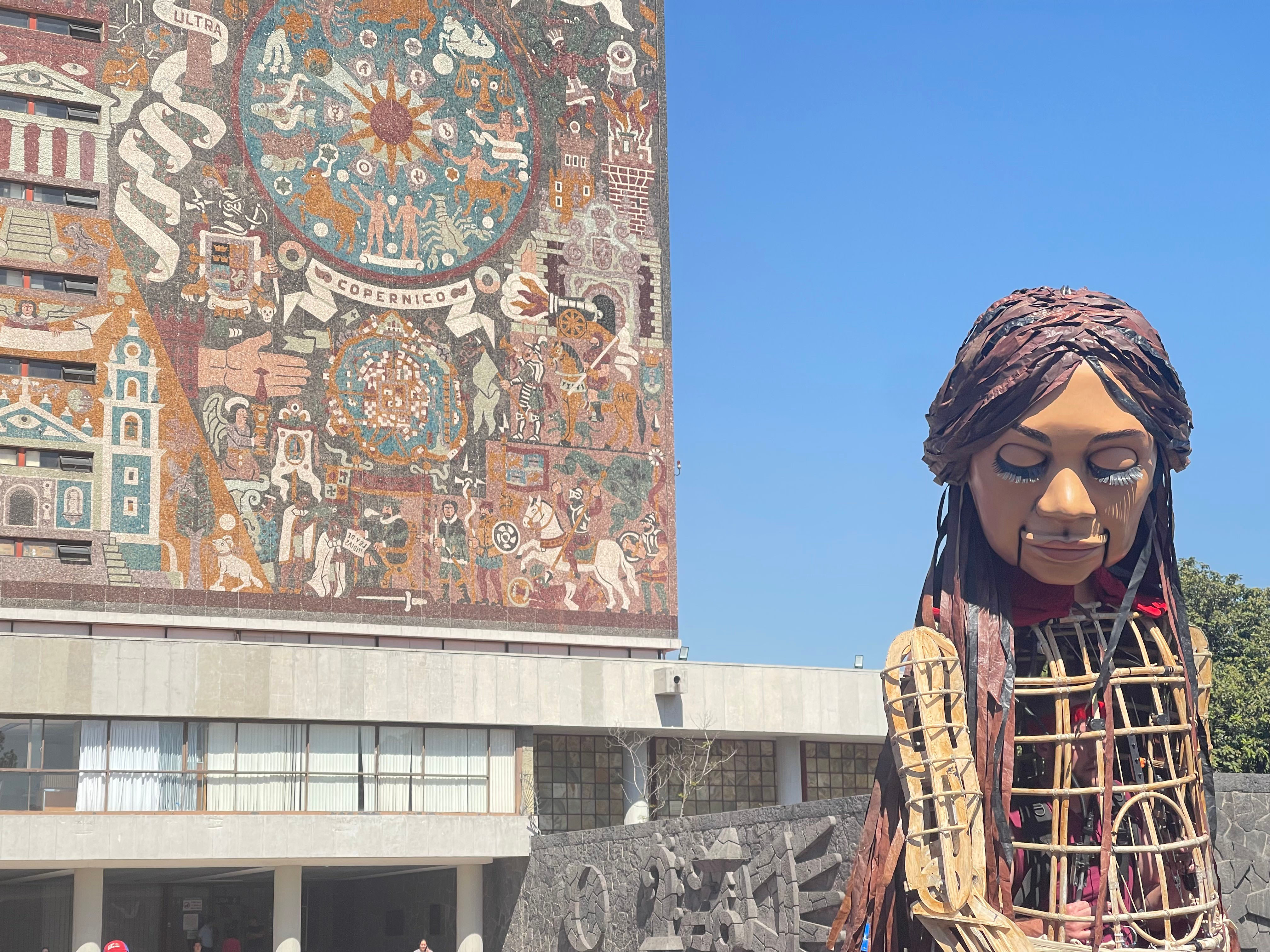 La pequeña Amal frente al icónico mural de Juan O'Gorman, en la UNAM.