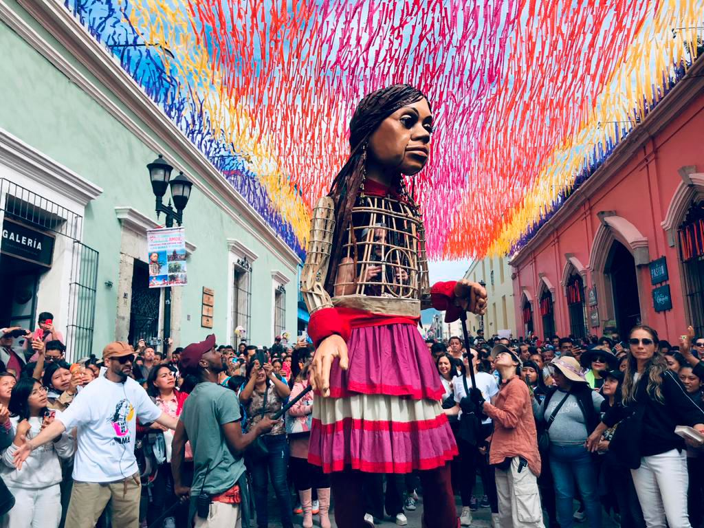 La pequeña Amal en el centro de Oaxaca rodeada por una multitud de personas.