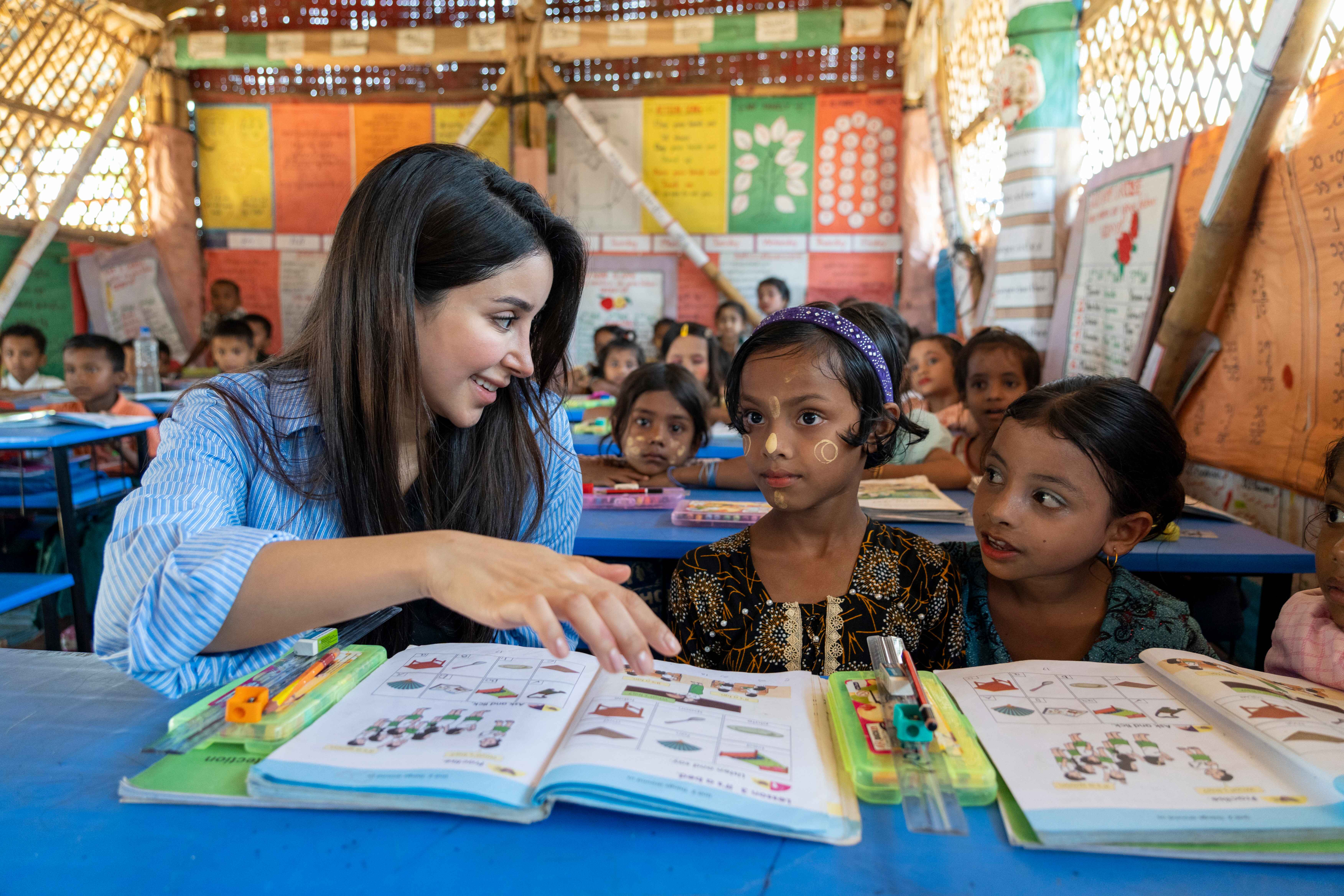 Una mujer saudita charla con dos niñas rohingya en un aula en Bangladesh