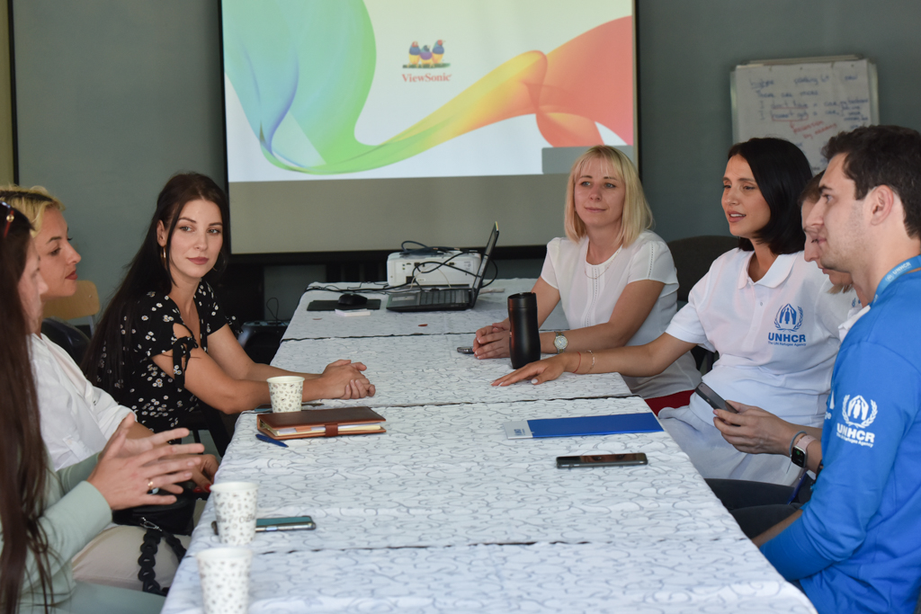 Una grupo de personas tiene una discusión en una mesa larga color blanco