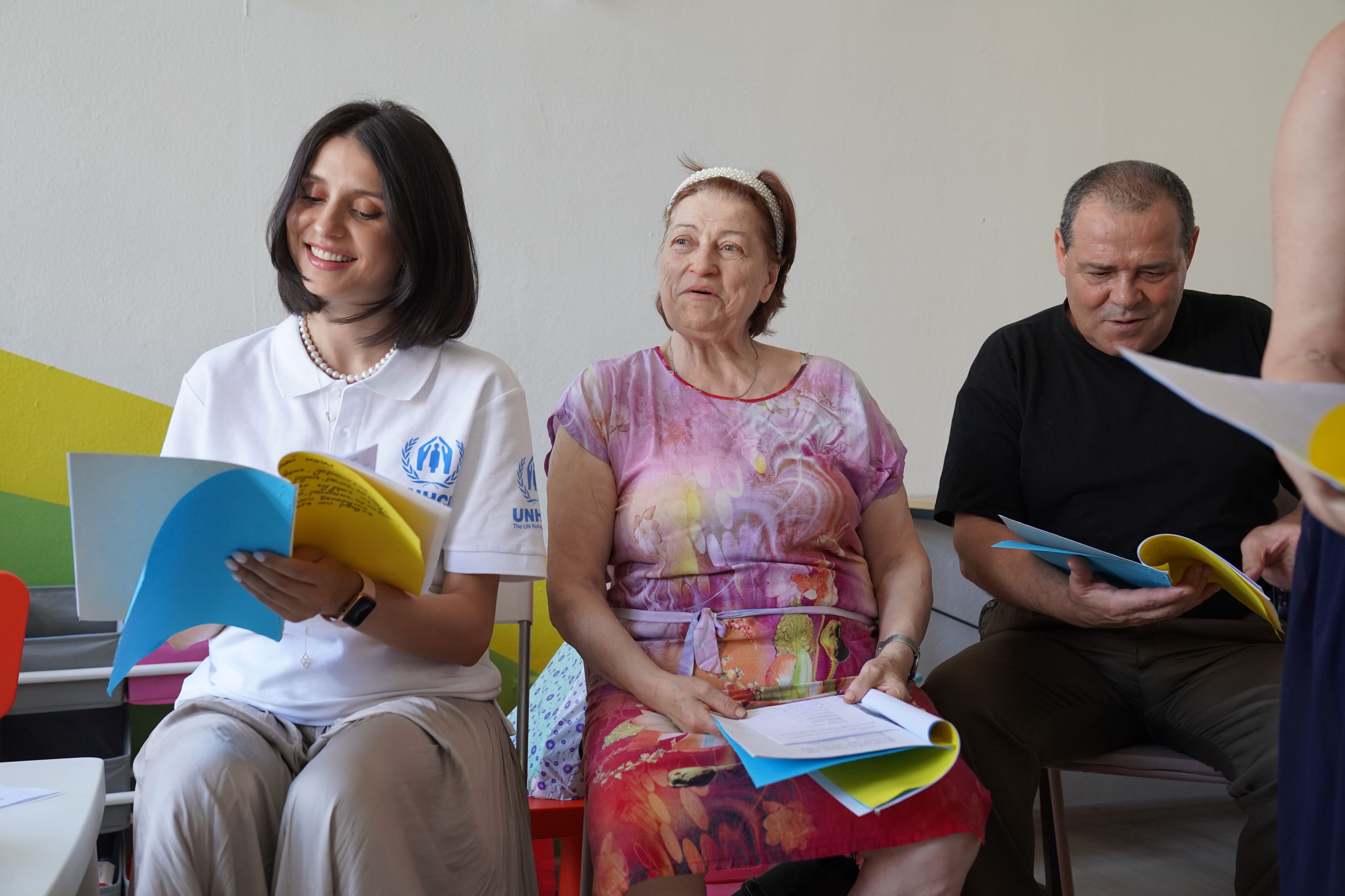Tres personas, dos mujeres y un hombre, están leyendo partituras sentadas una a lado de la otra