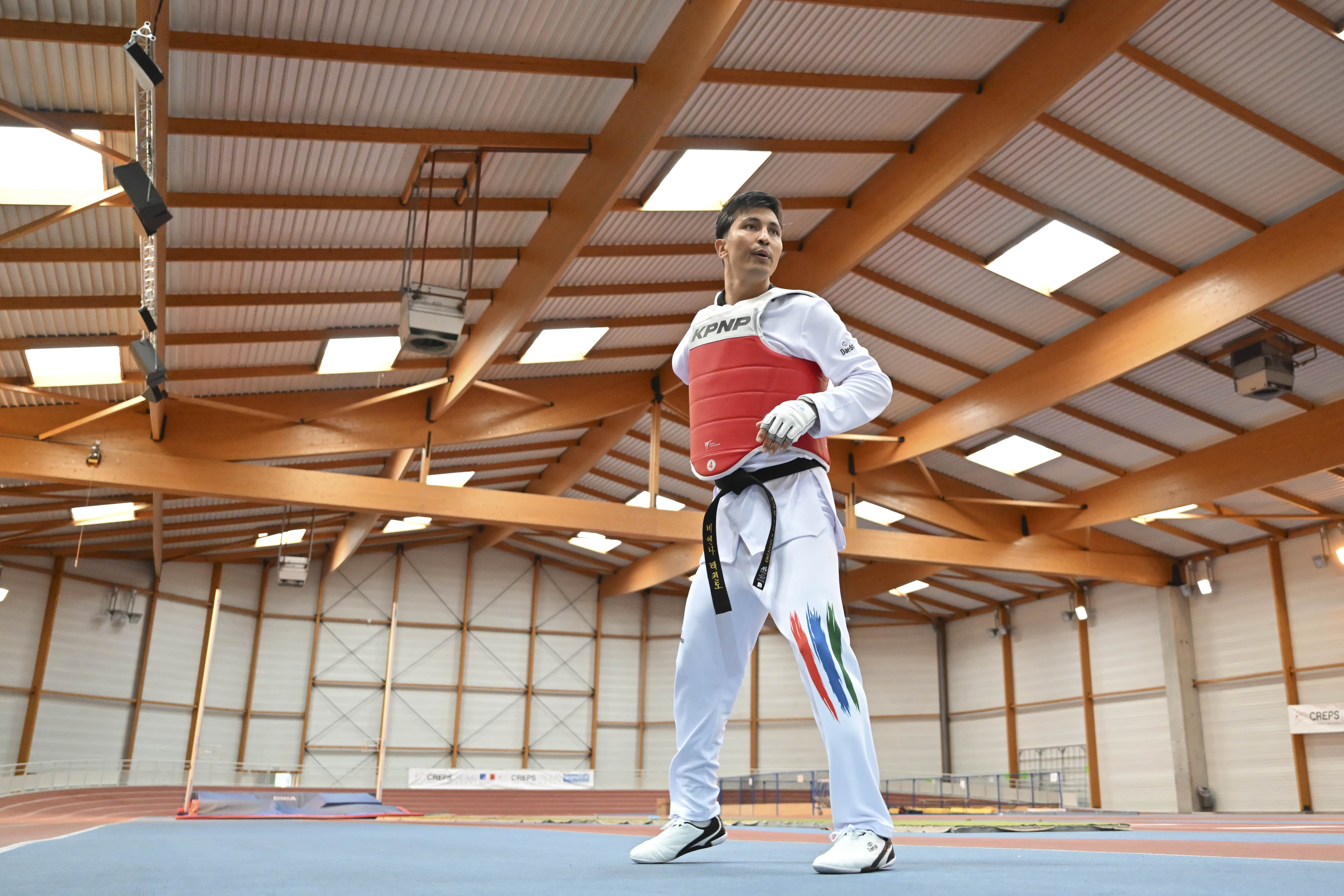 Un hombre con uniforme de taewkondo en un gimnasio