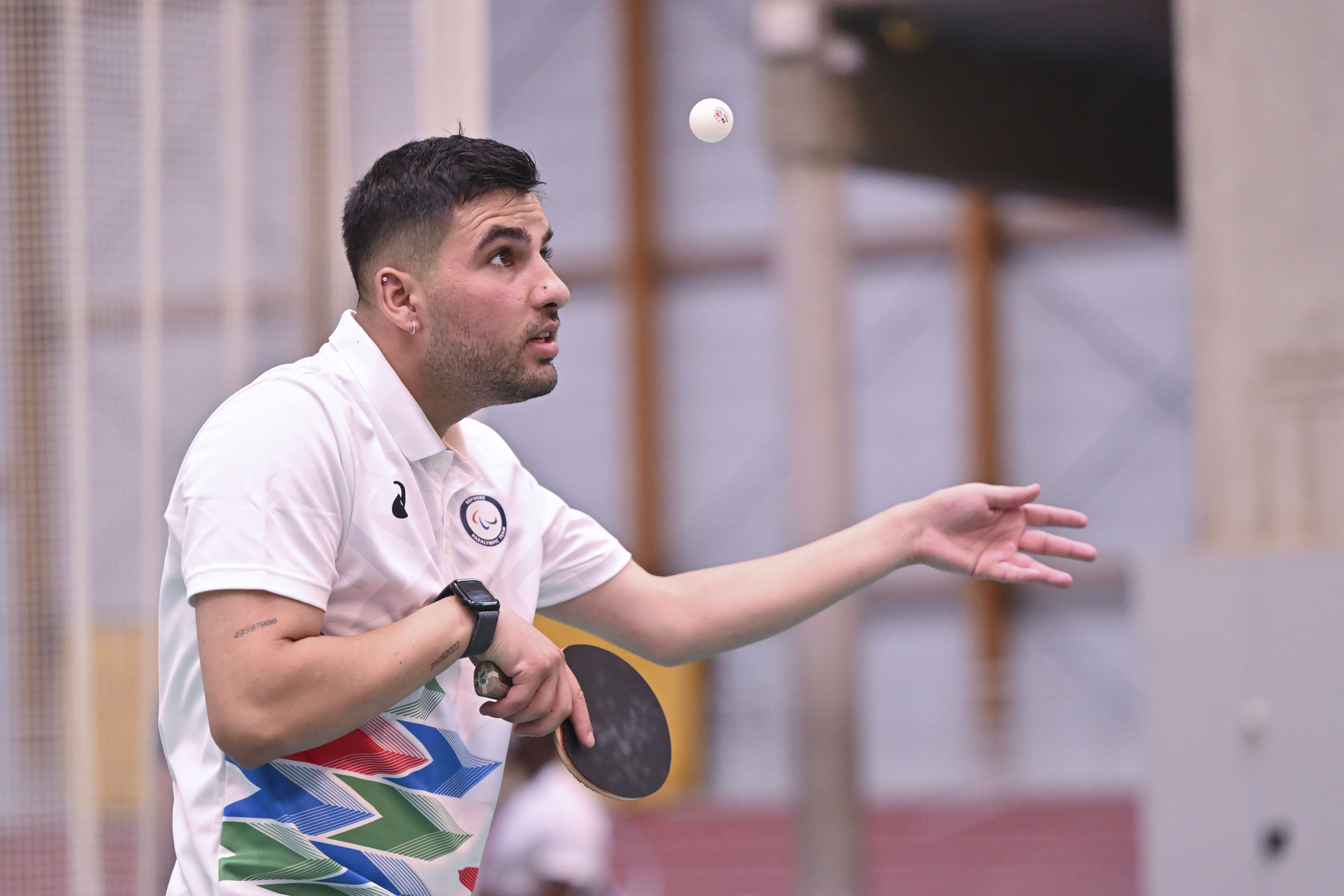Un hombre sostiene una raqueta de ping-pong con la mirada fija en una pelota