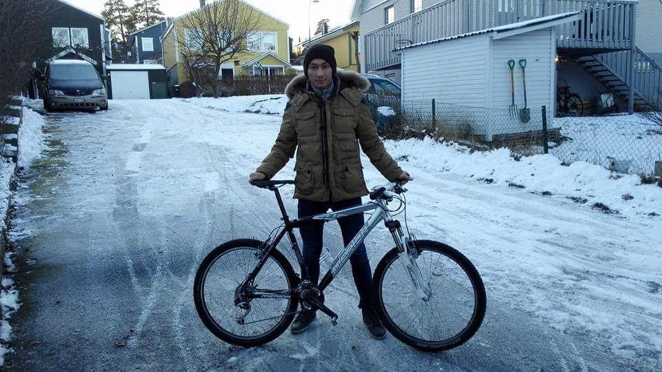 Un hombre en una calle nevada posa junto a una bicicleta
