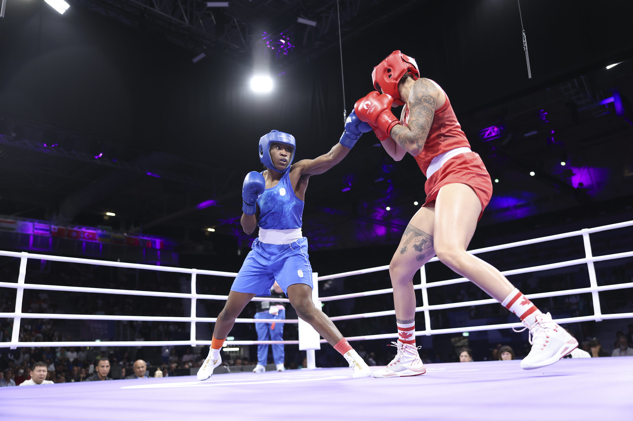 Una mujer vestida de azul lucha con una mujer vestida de rojo en un ring de boxeo