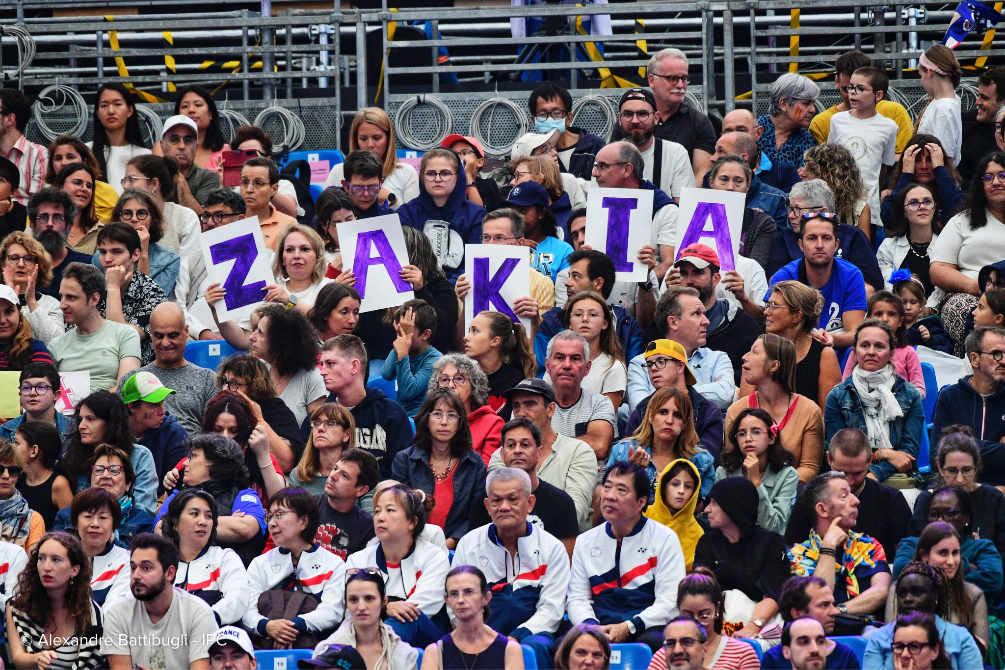 Un numeroso público sostiene carteles hechos a mano con las letras de Zakia