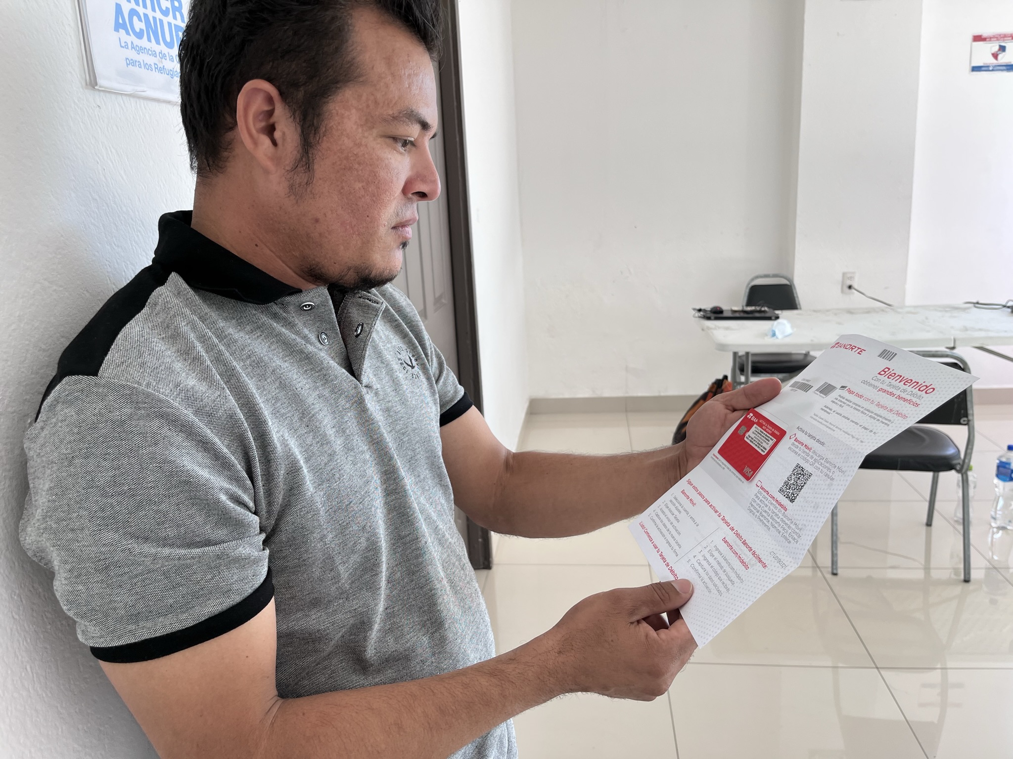 Un hombre joven sostiene un papel que contiene publicidad bancaria