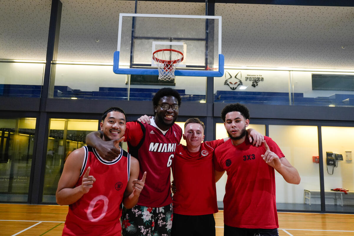 Cuatro jugadores de baloncesto que visten uniforme rojo, posan para la foto