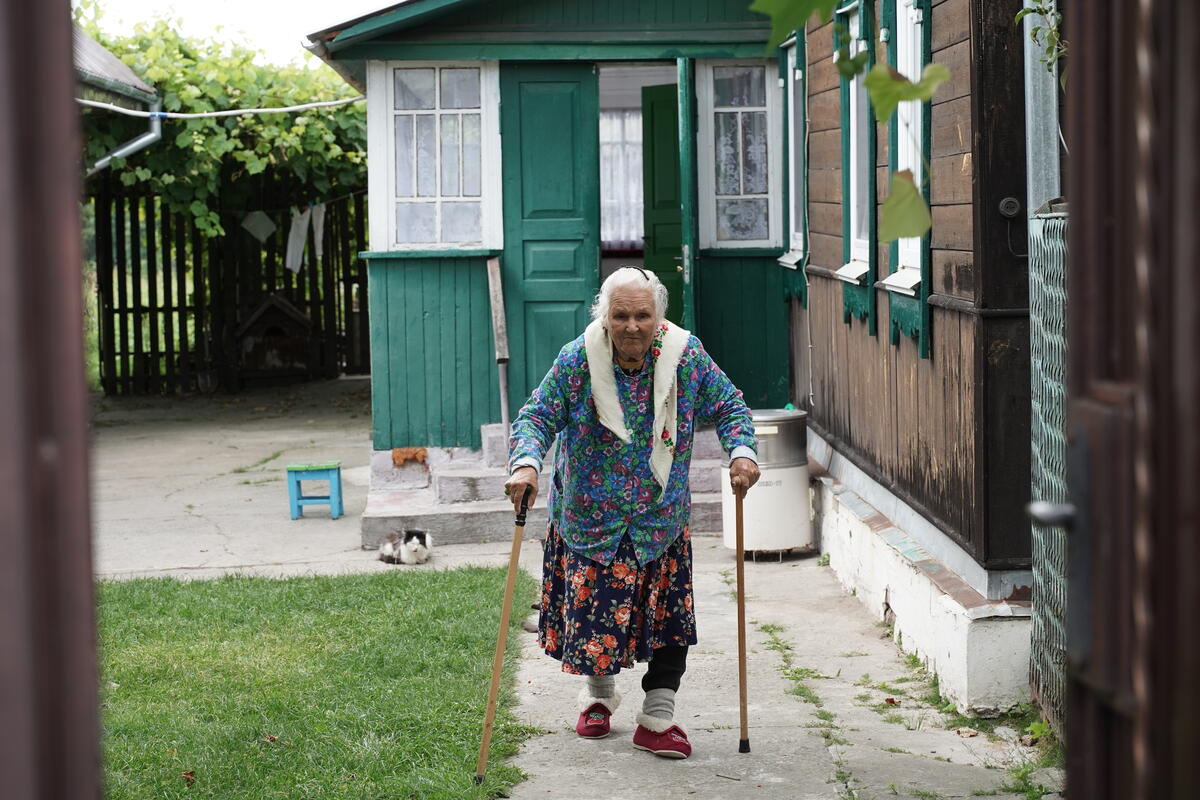 Halyna walks in the yard of her house that was repaired by UNHCR after it was destroyed as a result of subsequent hostilities. Halyna, 97, has lived in Kukhari village, Kyiv oblast, all her life. Her brothers and husband are buried here. She was forced to flee because of the full-scale war. After the Russian armed forces withdrew in April 2022, she returned home with her daughter, Nadiia, and Nadiia’s husband, Oleksandr, to find the house, with its pretty carved shutters, damaged. The windows and doors were shattered by artillery fire and bullets, and many of their personal belongings were either destroyed or stolen. During the spring of 2023, UNHCR, the UN Refugee Agency, helped the family repair their house. Windows were replaced and the roof was fixed, making the house habitable again and enabling Halyna to restore comfort in her home. Full story also published here: https://www.unhcr.org/ua/en/64307-restoring-kyiv-oblast-together.html Ucrania. ACNUR ayuda a reparar hogares afectados por la guerra