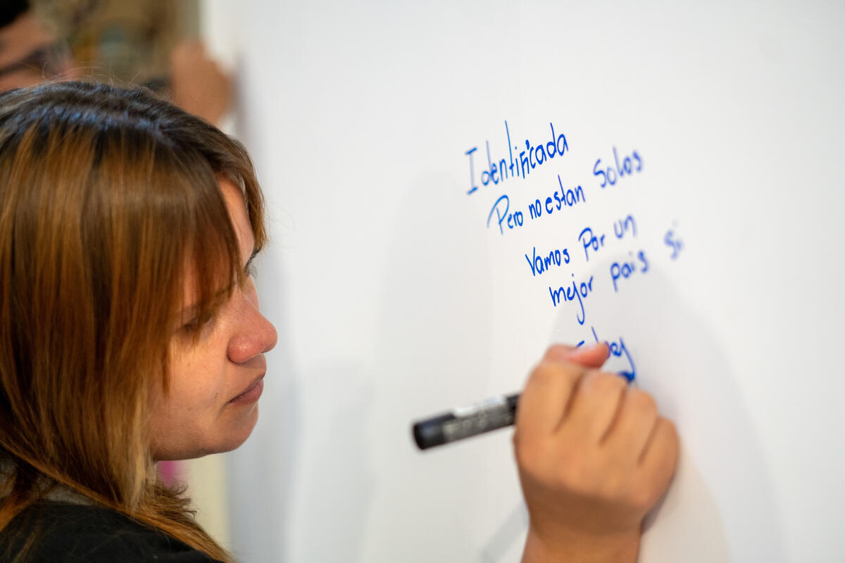 Una mujer escribe sobre un pintarrón blanco
