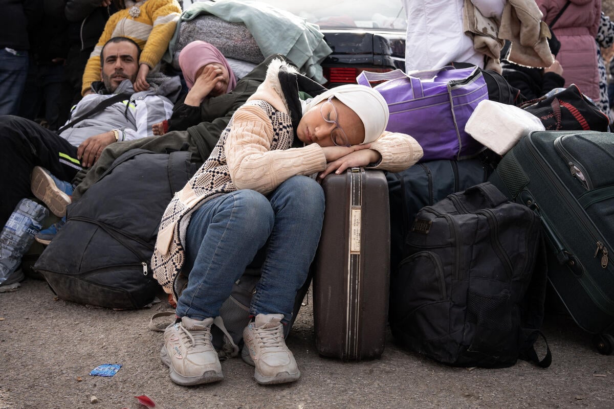 Una niña duerme sobre una maleta de viaje