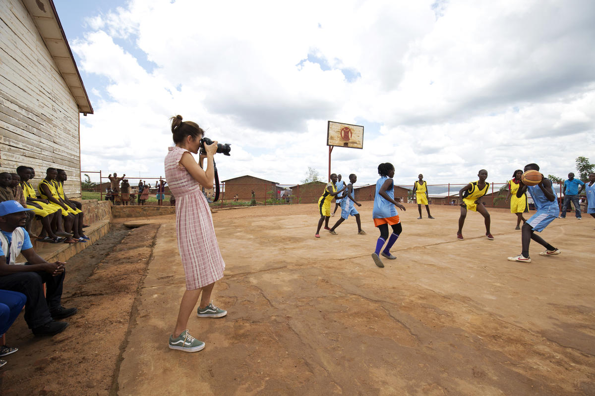 Una mujer fotografía a un grupo de niñas y niños que juegan baloncesto