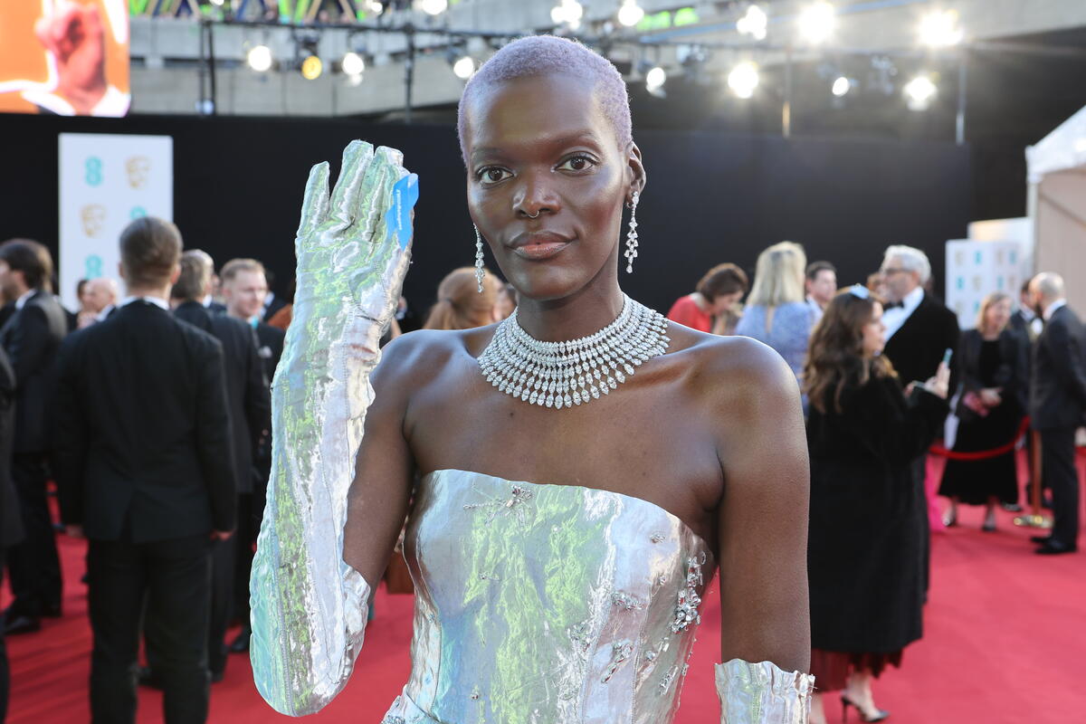 United Kingdom. Actor Sheila Atim wearing a blue ribbon in solidarity with refugees at the EE BAFTA Film Awards 2023
